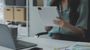 Ofiste çalışırken elinde tablet tutan genç iş kadını.