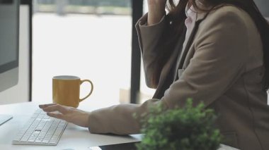 Kadın ofiste çalışırken sıcak kahve içiyor, dizüstü bilgisayar kullanıyor.