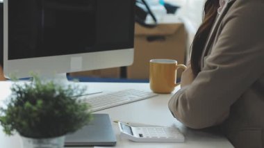 İş kadını masada oturuyor ve bilgisayar kullanıyor..