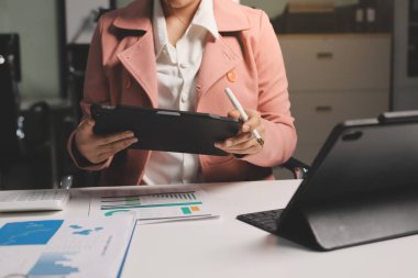 Ofisinde dizüstü bilgisayarla çalışan profesyonel bir iş kadınının görüntüsü. Genç bayan yönetici, modern çatı katında otururken taşınabilir bilgisayar kullanıyor. İşaret fişeği ışığı, iş süreci kavramı.