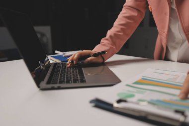 Ofisinde dizüstü bilgisayarla çalışan profesyonel bir iş kadınının görüntüsü. Genç bayan yönetici, modern çatı katında otururken taşınabilir bilgisayar kullanıyor. İşaret fişeği ışığı, iş süreci kavramı.