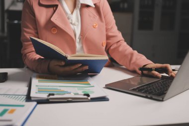 Ofisinde dizüstü bilgisayarla çalışan profesyonel bir iş kadınının görüntüsü. Genç bayan yönetici, modern çatı katında otururken taşınabilir bilgisayar kullanıyor. İşaret fişeği ışığı, iş süreci kavramı.