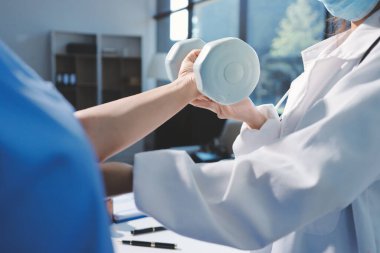 Evde oturma odasında terapi ve rehabilitasyon görürken, bakıcı ya da fizyoterapist yaşlılara yardım ederken, son sınıf öğrencisi olan Asyalı bir kadın ya da hemşire kol egzersizi için halteri kaldırıyor..