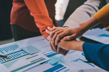 İş adamları ve iş kadınları, takım çalışması, destek ve iş birliğini gösteren çok kültürlü ofis odasındaki grup toplantılarında el ele tutuşuyorlar. Çeşitlilik işyeri