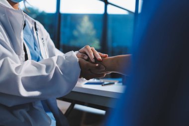 Yakın plan, doktor yaşlı bir kadınla el ele tutuşuyor ve kanser bakımı ya da destek. Sağlık hizmetleri veya güven, empati veya şefkat ve kadın bakıcı veya hemşire umut ve şefkat için yaşlı kişinin elini tutuyor.