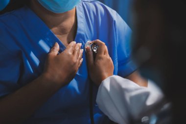 Ev bakımı hemşiresi ve yaşlılar kardiyoloji sağlık hizmetleri. Genç İspanyol kadın doktor hemşirenin yakın çekimleri sırasında steteskop kullanarak olgun beyaz hasta kalp atışlarını kontrol et.