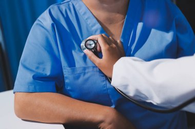 Ev bakımı hemşiresi ve yaşlılar kardiyoloji sağlık hizmetleri. Genç İspanyol kadın doktor hemşirenin yakın çekimleri sırasında steteskop kullanarak olgun beyaz hasta kalp atışlarını kontrol et.