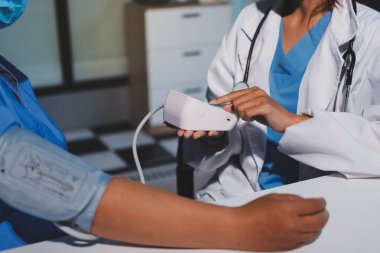 Steteskopla sfenometre kullanan bir doktor hastanede kan basıncını ölçüyor..