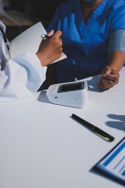 Steteskopla sfenometre kullanan bir doktor hastanede kan basıncını ölçüyor..