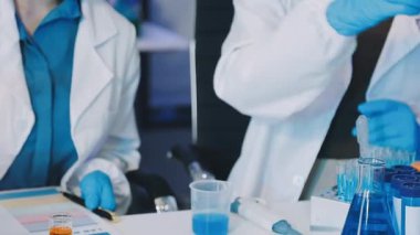 Mavi ceketli laboratuvar asistanı ve matarada beyaz sıvı.