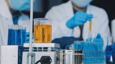 Laboratuvar araştırması, bilim ve araştırma konsepti. Yakın plan - laboratuvar önlüklü bir erkek bilim adamı ve arka planda pipetli eldivenler