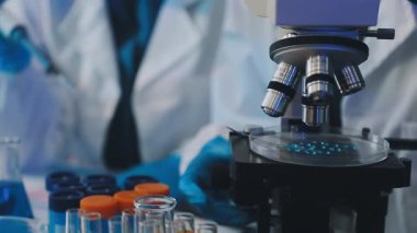 Bilim adamı laboratuvarda bir mikroskop tutuyor..