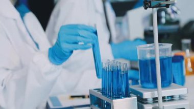 Bilim adamı elinde sıvı olan bir tüp tutuyor.