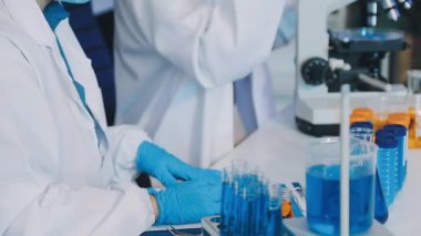 Laboratuvar çalışanı ellerinde bir bardak su tutuyor..