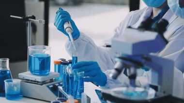 Mavi ceketli bilim adamı elinde sıvı olan tüpü tutuyor.