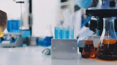 Koruyucu eldivenler ve koruyucu eldivenler giyen bilim adamı kimya laboratuvarında sıvıyla çalışıyor..