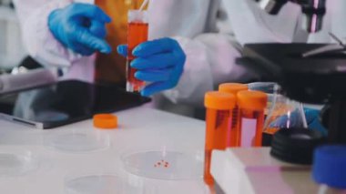 Laboratuvarda koruyucu eldivenli bir bilim adamı kan tüpü tutuyor..