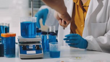 Laboratuvarda laboratuvar test tüpleriyle çalışan koruyucu eldivenler giyen bilim adamı.