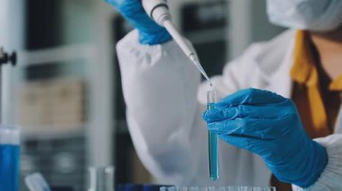 Laboratuvarda sıvı içeren test tüpü tutan bilim adamının yakın çekim görüntüsü.