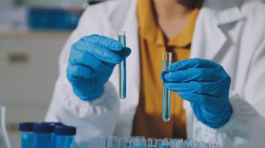 Laboratuvar önlüklü bilim adamı laboratuarda sıvı test tüpü tutuyor.