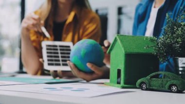 Elinde kağıt ev modeli tutan ve elinde yeşil enerji gösteren genç bir kadın..