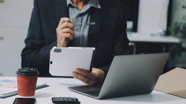 Elinde tablet olan ve ofiste çalışan genç adamın yakın görüntüsü.