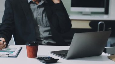 İşadamı ofiste dizüstü bilgisayar ve hesap makinesiyle çalışıyor.