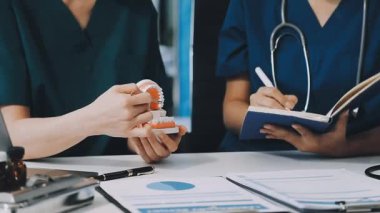 Kadın doktor, klinikte asistanıyla bir hastaya danışmanlık yapıyor.