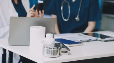 Ofisinde steteskop ve dizüstü bilgisayarı olan bir doktor var. Doktor dizüstü bilgisayarla çalışıyor..