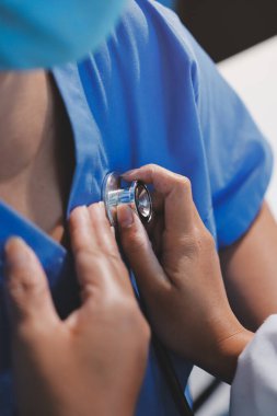 Ev bakımı hemşiresi ve yaşlılar kardiyoloji sağlık hizmetleri. Genç İspanyol kadın doktor hemşirenin yakın çekimleri sırasında steteskop kullanarak olgun beyaz hasta kalp atışlarını kontrol et.