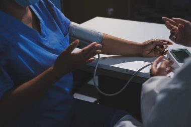 Steteskopla sfenometre kullanan bir doktor hastanede kan basıncını ölçüyor..