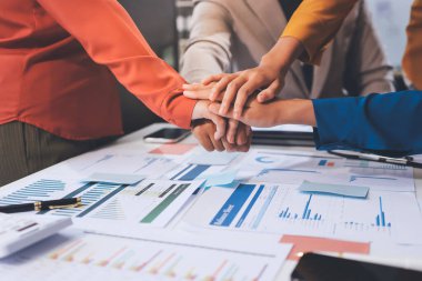 İş adamları ve iş kadınları, takım çalışması, destek ve iş birliğini gösteren çok kültürlü ofis odasındaki grup toplantılarında el ele tutuşuyorlar. Çeşitlilik işyeri