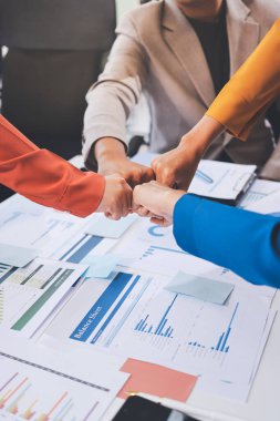 İş adamları ve iş kadınları, takım çalışması, destek ve iş birliğini gösteren çok kültürlü ofis odasındaki grup toplantılarında el ele tutuşuyorlar. Çeşitlilik işyeri