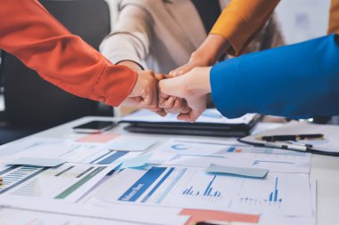 İş adamları ve iş kadınları, takım çalışması, destek ve iş birliğini gösteren çok kültürlü ofis odasındaki grup toplantılarında el ele tutuşuyorlar. Çeşitlilik işyeri