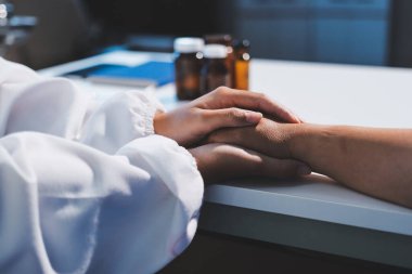 Yakın plan, doktor yaşlı bir kadınla el ele tutuşuyor ve kanser bakımı ya da destek. Sağlık hizmetleri veya güven, empati veya şefkat ve kadın bakıcı veya hemşire umut ve şefkat için yaşlı kişinin elini tutuyor.