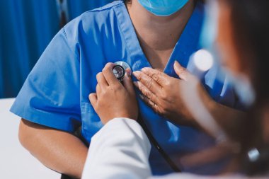 Ev bakımı hemşiresi ve yaşlılar kardiyoloji sağlık hizmetleri. Genç İspanyol kadın doktor hemşirenin yakın çekimleri sırasında steteskop kullanarak olgun beyaz hasta kalp atışlarını kontrol et.