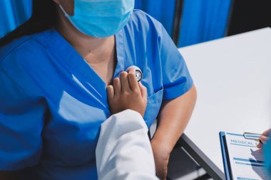 Ev bakımı hemşiresi ve yaşlılar kardiyoloji sağlık hizmetleri. Genç İspanyol kadın doktor hemşirenin yakın çekimleri sırasında steteskop kullanarak olgun beyaz hasta kalp atışlarını kontrol et.