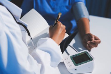 Steteskopla sfenometre kullanan bir doktor hastanede kan basıncını ölçüyor..