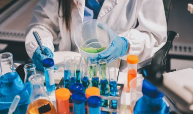 Bilimadamı laboratuarda tıbbi örnekleri mikro plakaya yerleştiriyor.