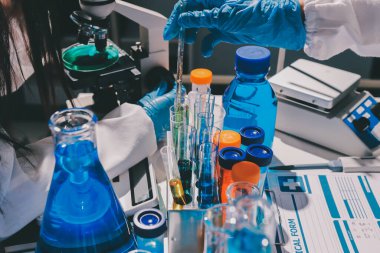 Bilimadamı laboratuarda tıbbi örnekleri mikro plakaya yerleştiriyor.