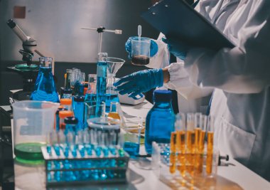 Bilimadamı laboratuarda tıbbi örnekleri mikro plakaya yerleştiriyor.