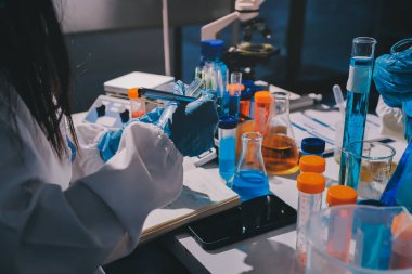 Bilimadamı laboratuarda tıbbi örnekleri mikro plakaya yerleştiriyor.