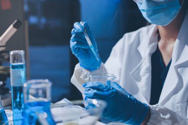 Bilimadamı laboratuarda tıbbi örnekleri mikro plakaya yerleştiriyor.