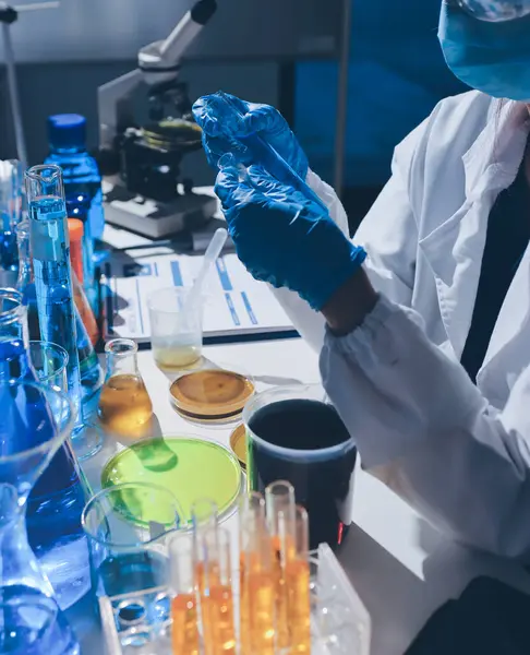 Bilimadamı laboratuarda tıbbi örnekleri mikro plakaya yerleştiriyor.