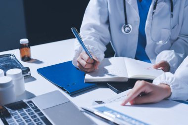 Erkek ve kadın doktorlar bir hastane odasında toplantı yapıyorlar..