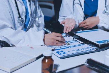 Erkek ve kadın doktorlar bir hastane odasında toplantı yapıyorlar..