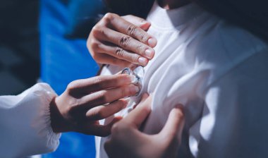 Konuşurken kalp atışı ve semptomlarını incelemek için steteskop kullanan erkek doktorun el görüntüsü.