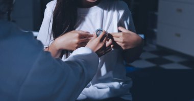 Konuşurken kalp atışı ve semptomlarını incelemek için steteskop kullanan erkek doktorun el görüntüsü.