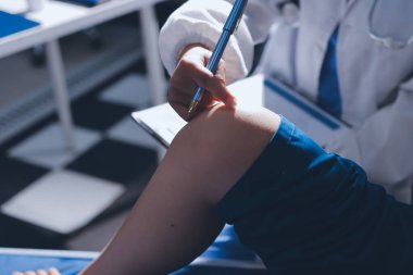 Kadın doktor elleri, erkek bir hastanın bacağını ve dizini uzatarak fizik tedavi uyguluyor.