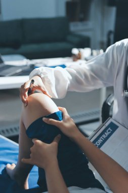 Kadın doktor elleri, erkek bir hastanın bacağını ve dizini uzatarak fizik tedavi uyguluyor.